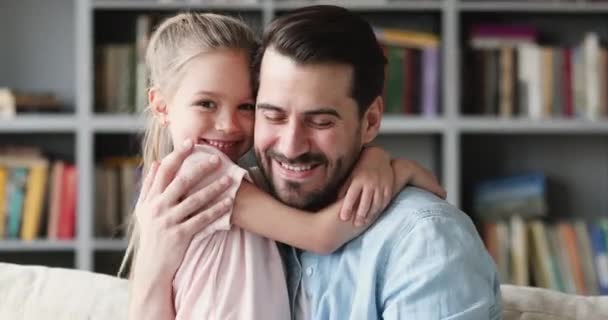 Lächelnder Vater umarmt kleine fröhliche Tochter zu Hause. — Stockvideo