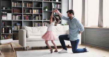 Gülümseyen genç baba dizlerinin üzerinde mutlu kızı büküyor..