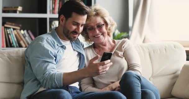 Homem feliz mostrando crianças fotos engraçadas para a mãe mais velha . — Vídeo de Stock