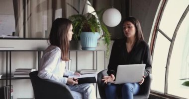 Hintli ve Kafkas kadın iş arkadaşları sandalyelerde oturma projesini tartışıyor