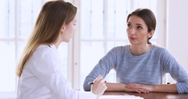 Kadın sağlık görevlisini dinleyen odaklanmış genç bir hasta..