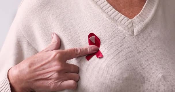 Close up mature old woman applied red ribbon to chest. — Stock Video