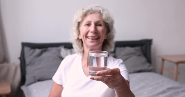 Sorridente donna anziana che mostra un bicchiere d'acqua e pollici in su . — Video Stock