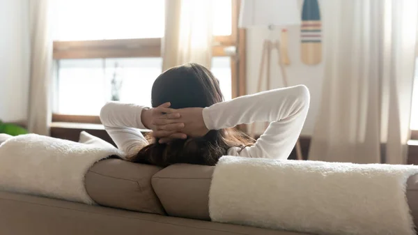 Visão traseira da mulher relaxar no sofá olhando à distância — Fotografia de Stock