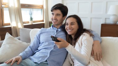 Mutlu çift kanepede televizyon seyrediyor.