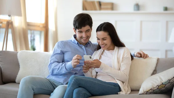 Glückliches Paar ruht sich per Smartphone auf Sofa aus — Stockfoto