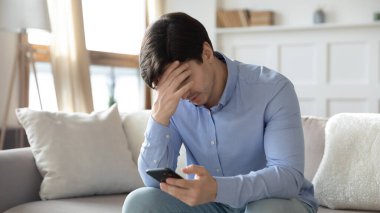 Üzgün adam akıllı telefondan nahoş bir mesaj alıyor.