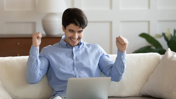 Aufgeregter junger Mann gewinnt Online-Lotterie auf Laptop — Stockfoto