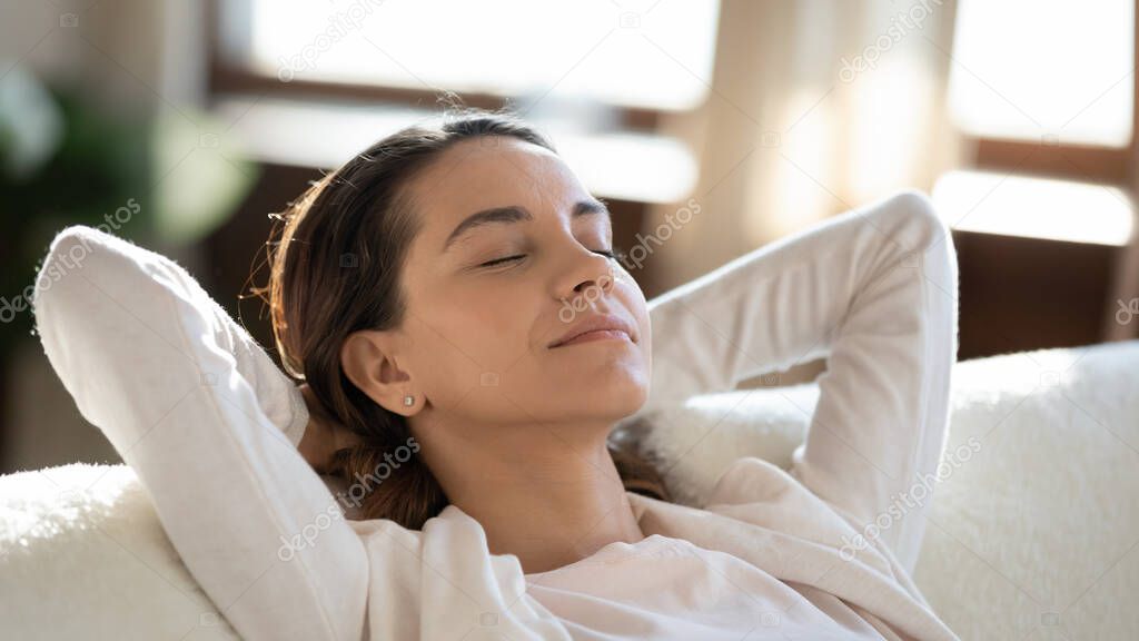 Calm young woman relax on couch dreaming