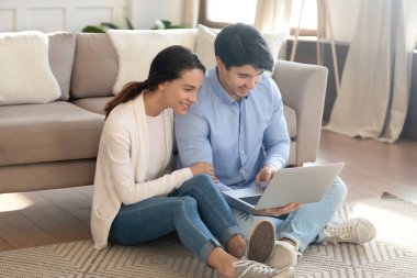 Genç çift evde dizüstü bilgisayar kullanıyor.