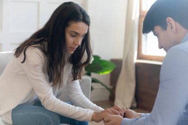 Üzgün genç çift aile içi sorunlar yaşarken el ele tutuşuyorlar.