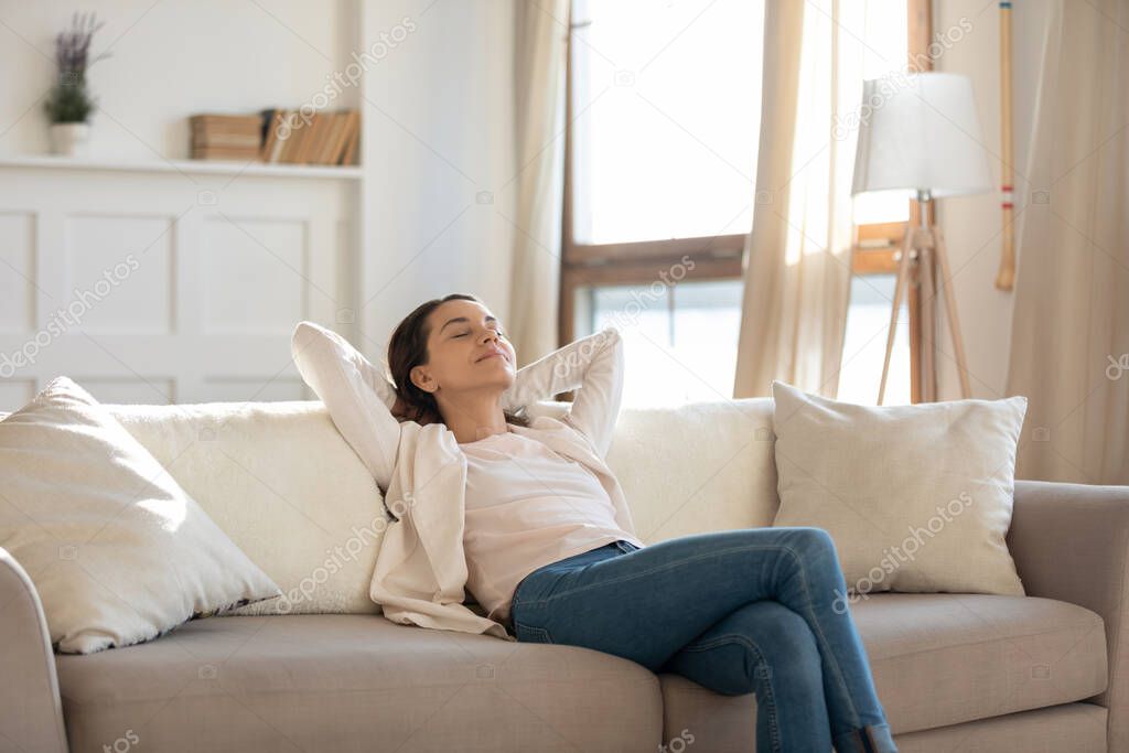 Relaxed young woman rets on sofa enjoying weekend