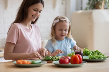 Küçük kızıyla evde yemek pişiren bir anne.