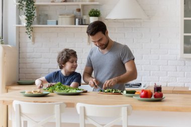 Sevecen baba ve küçük oğul mutfakta birlikte yemek pişiriyorlar.