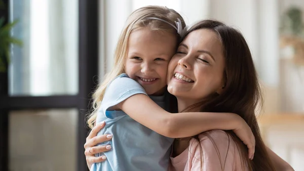 Bonne petite fille câlin souriant jeune maman montrant des soins — Photo