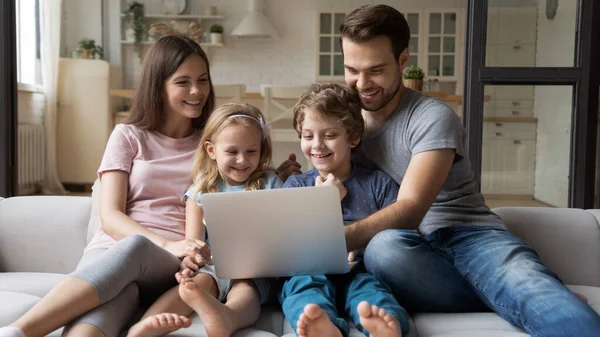 Happy young family with kids watch video on laptop