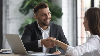 Güler yüzlü iş adamı, toplantıda müşteri elini sıkıyor.