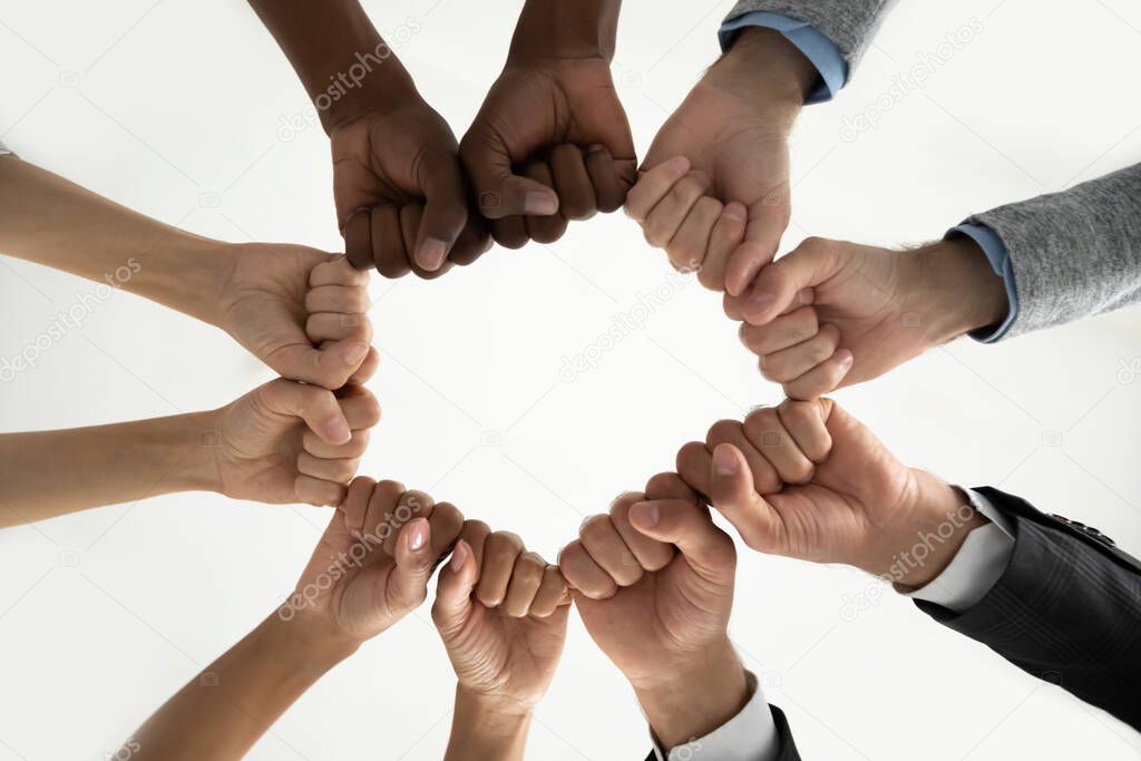 Close up diverse employees team holding fists in circle