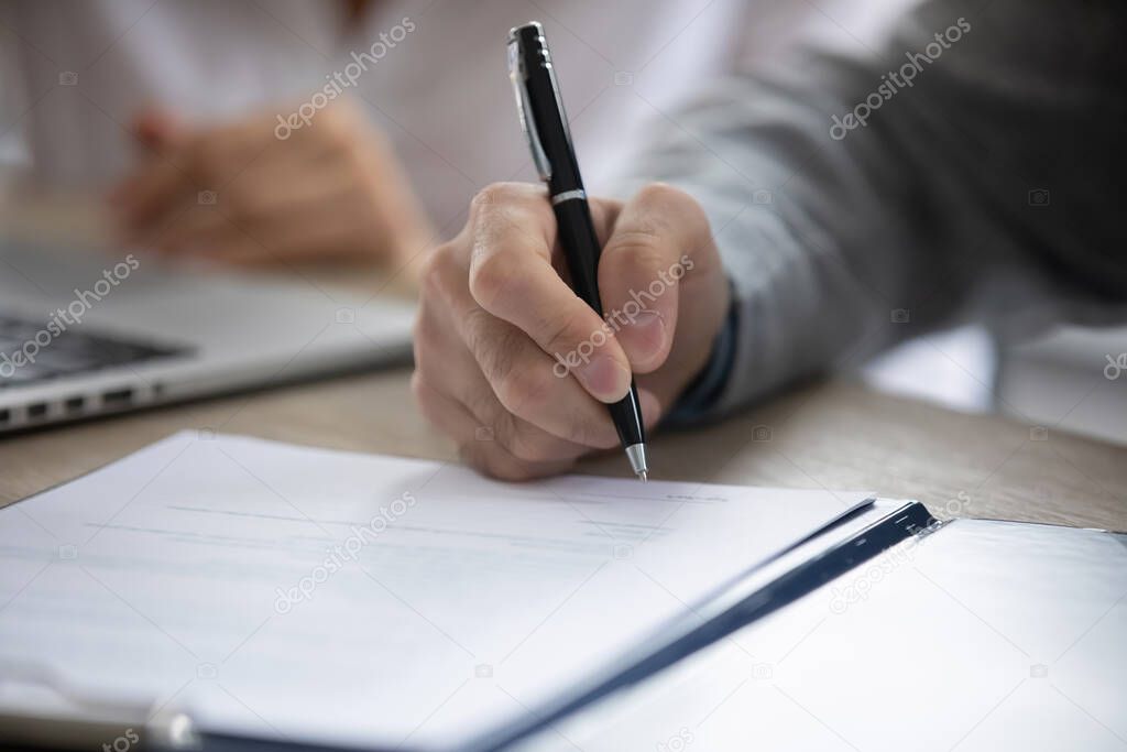 Close up male hand holding pen, business man signing contract