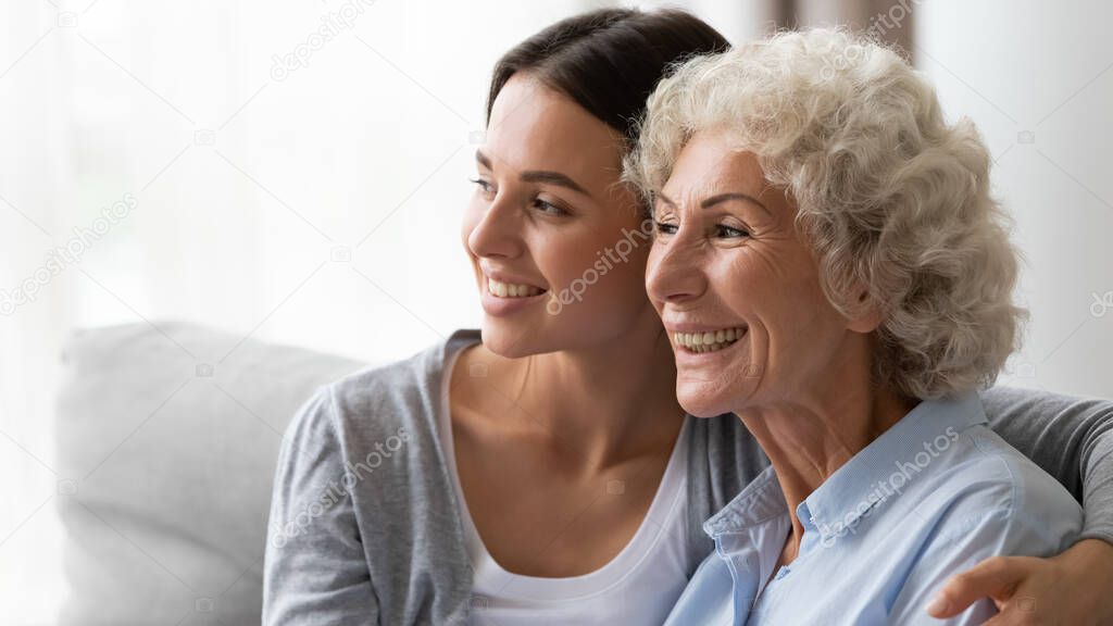 Horizontal image adult granddaughter hugs elderly grandmother