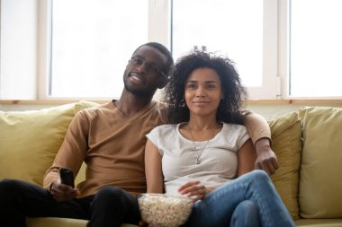 Kanepede oturup patlamış mısır yiyen çift TV 'de film izliyor.