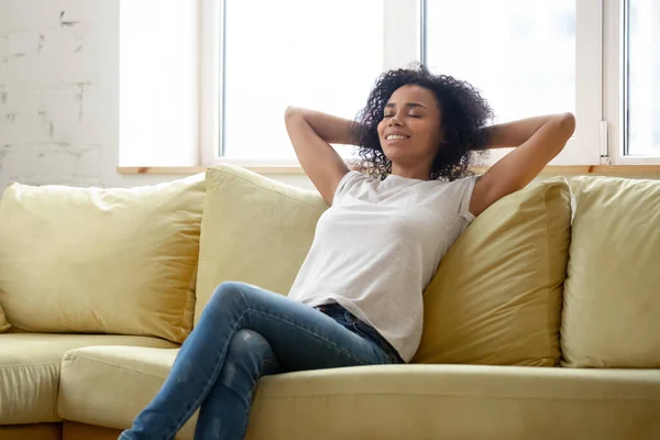 Wanita Afrika yang damai beristirahat di sofa di ruang tamu modern — Stok Foto