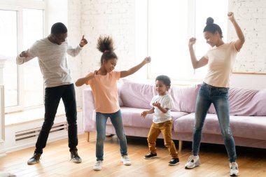 Modern oturma odasında çocuklu Afrikalı bir aile dans ediyor.