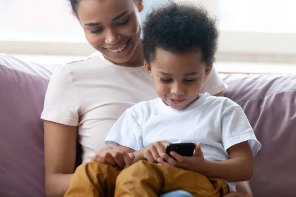 Son sit on mothers lap using smartphone play games