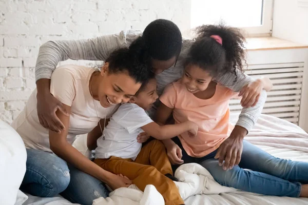 Família africana jogando jogos ativos engraçados com crianças na cama — Fotografia de Stock