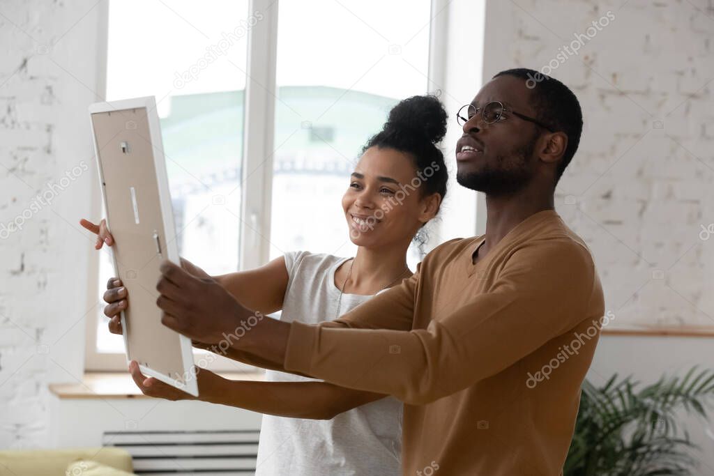 Couple hanging photo frame during relocation day at new home