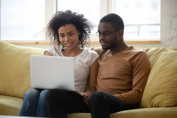 Pareja africana descansando en el sofá viendo la película en el portátil —  Fotos de Stock