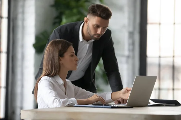 Businesswoman intern asking questions about project to serious confident mentor