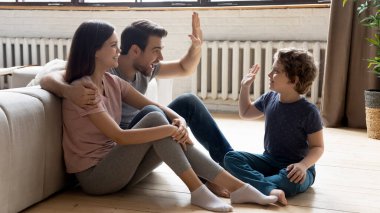 Gülümseyen genç ebeveynler evde küçük oğullarıyla rahatlar.