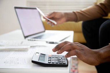 African man calculates expenses using calculator closeup image clipart