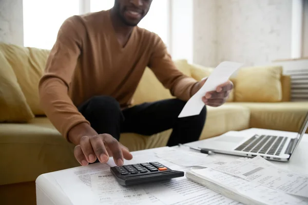 African ethnicity man calculates digits using calculator planning family budget — Stock Photo, Image