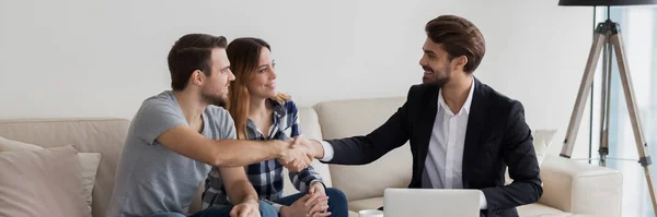 Gelukkig jong stel flat renters schudden handen met makelaar — Stockfoto