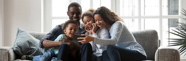 African ethnicity family with little kids having fun using smartphone — Stock Photo, Image