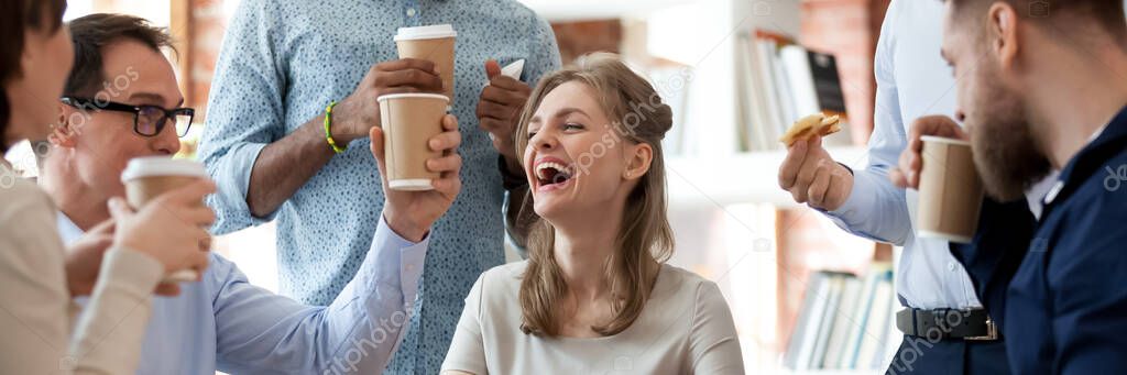 Group of cheerful colleagues eat pizza drink coffee during break