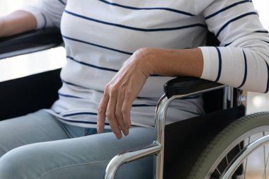 Yaşlanmış engelli kadın tekerlekli sandalyede dinleniyor. Yakın çekimde kırpılmış manzara.