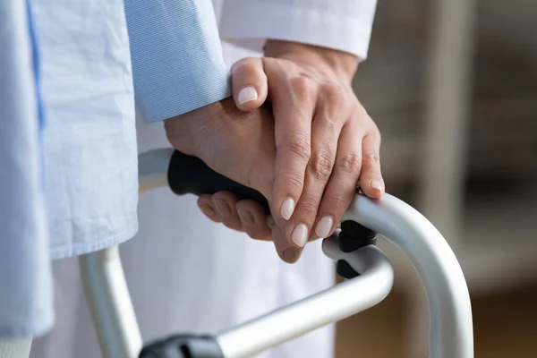 Fisioterapista tocca mano donna mentre tiene in mano telaio a piedi primo piano — Foto Stock