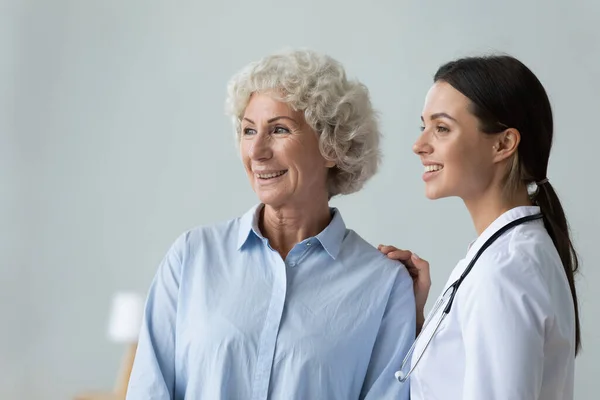 Nurse puts hand on shoulder of elderly patient showing care