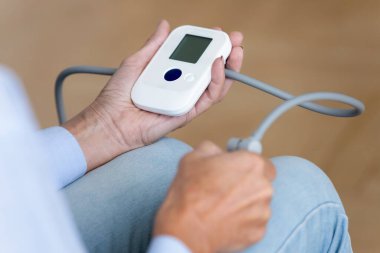 Yaşlı kadın kan basıncını sphygmomanometre cihazıyla izliyor. Görüntüyü kapat.