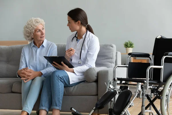 Doctor consulting disabled aged patient explain diagnosis during visit