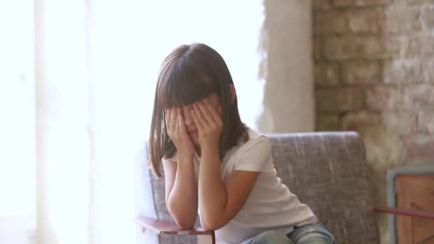Маленькая очаровательная дошкольница, сидящая на кресле, расстроена. — стоковое видео