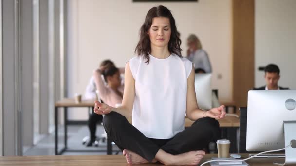 Worker do meditation sitting in lotus position on office desk — Stock Video