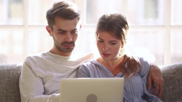 Millennial-Paar sitzt auf Couch und stöbert im Internet — Stockvideo
