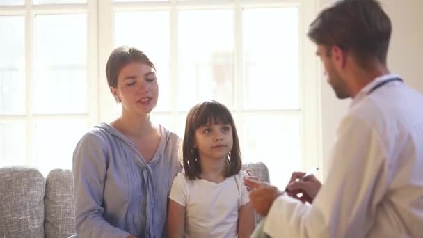 Médico mãe escutando de filha pequena durante a visita na clínica — Vídeo de Stock