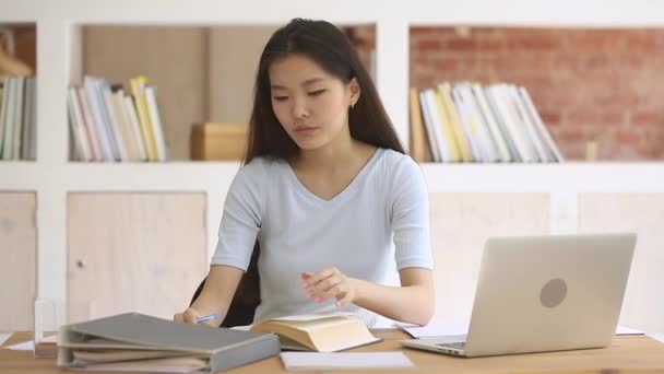 Focused asian teen student studying writing notes doing research homework — Stock Video