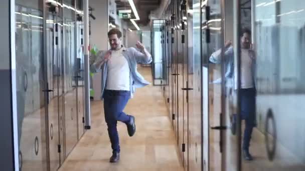 Веселый энергичный молодой бизнесмен, танцующий в одиночестве в коридоре — стоковое видео