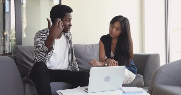 Африканский наставник объясняет онлайн-проект азиатскому интерну с ноутбуком — стоковое видео